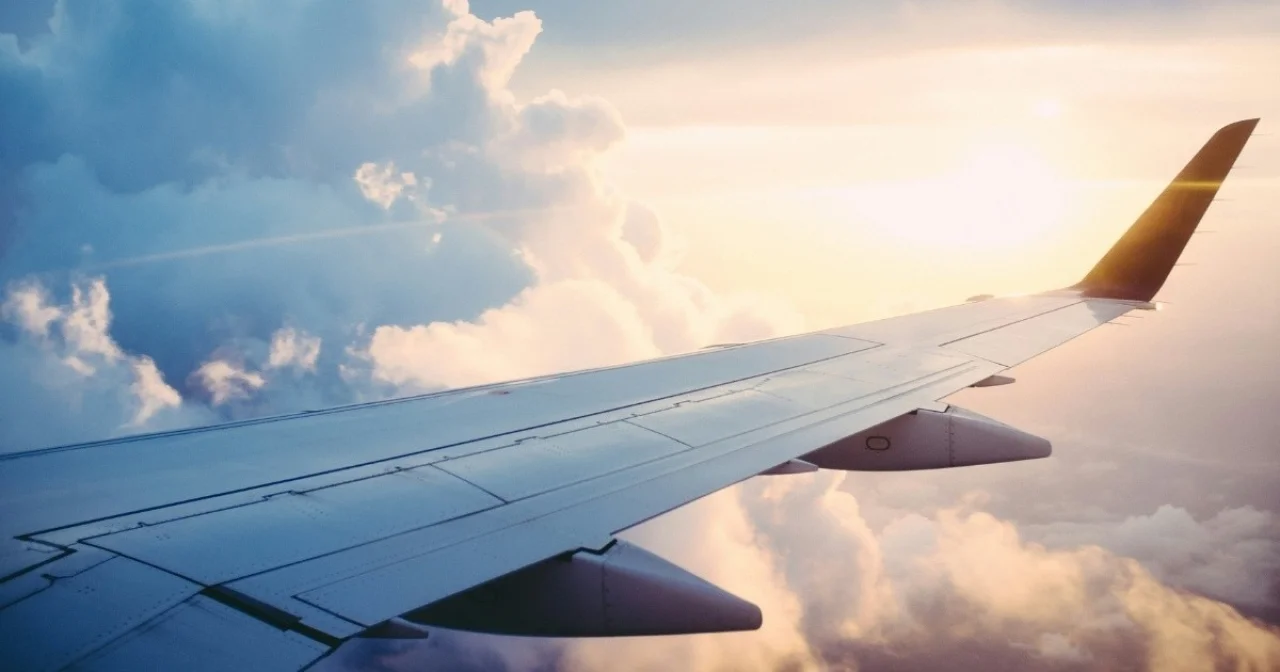 Ausblick auf Flugzeugfenster auf Tragflächen und Wolken