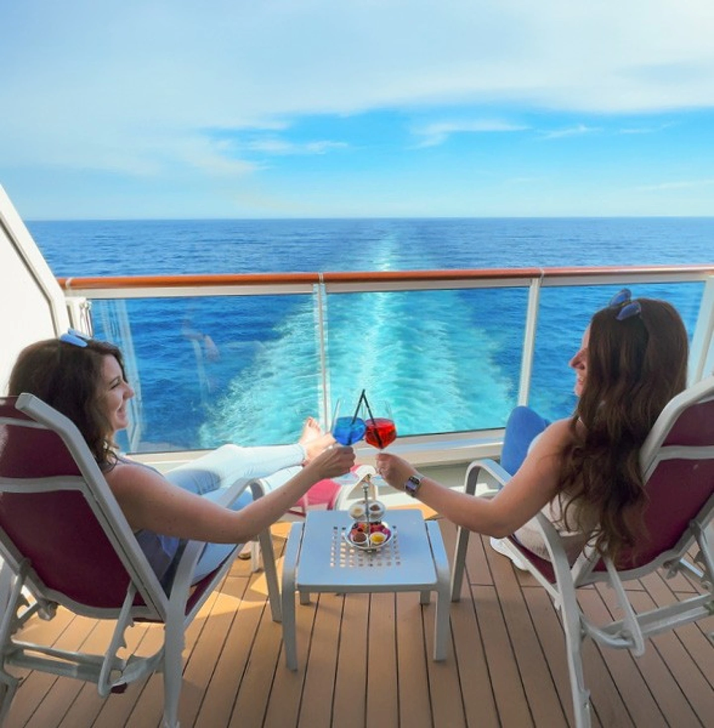Katharina und Rebekka von EURESAreisen stoßen mit Cocktail auf Kabinenbalkon eines Kreuzfahrtschiffes an